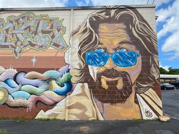 The Big Lebowski The Dude Abides Mural in West Asheville with the character The Dude from the movie as a white male with sandy brown blonde hair, blue sunglasses, and goatee