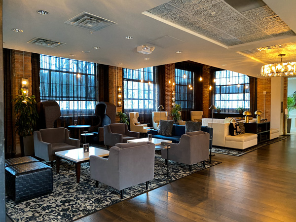 The Foundry Hotel Asheville NC Lounge with gray chairs with white tables and large windows with brick walls and yellow lighting