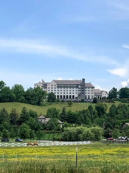 The Inn On Biltmore Estate with hotel on hill, green grass, and two horses