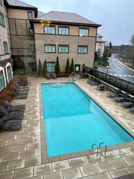 Village Hotel on Biltmore Estate in Asheville blue outdoor pool and brown and tan facade of building with fence out front