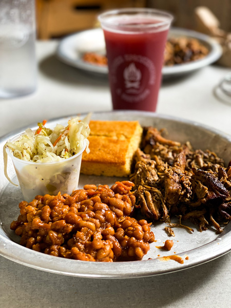 12 Bones Smokehouse BBQ Asheville Pulled Pork Platter with corn bread, slaw, baked beans, and blueberry beer in plastic cup