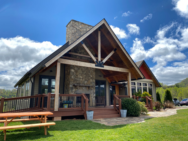 Addison Farms Vineyard Near Asheville with large house and tasting room, green grass, blue cloudy sky, and picnic tables