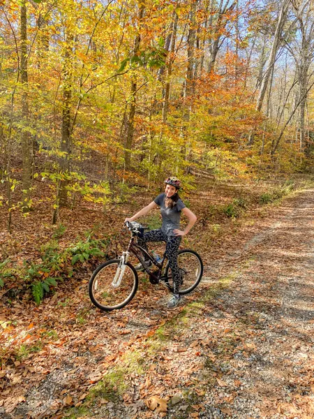 Bent Creek Experimental Forest Mountain Biking Trails Asheville with white brunette woman on purple mountain bike on trail surrounded by fall foliage