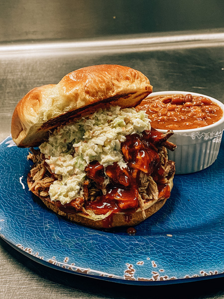 Big South Kitchen BBQ Asheville Pulled Pork Sandwich with baked beans on blue plate