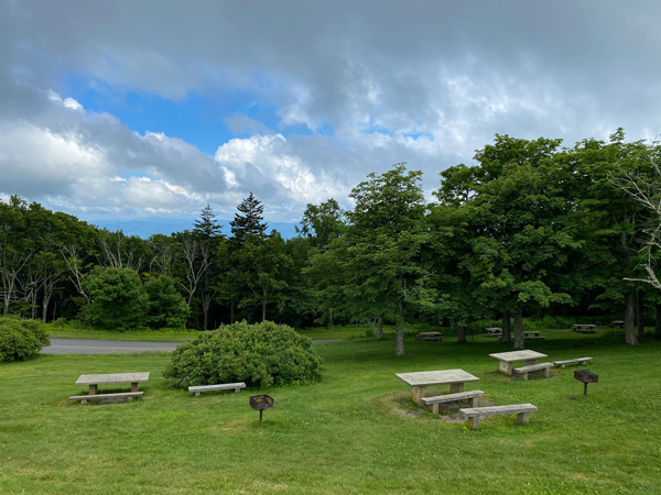 Craggy Gardens Picnic Spots Blue Ridge Parkway with green grass and blue cloudy sky with picnic tables spread out and charcoal grills