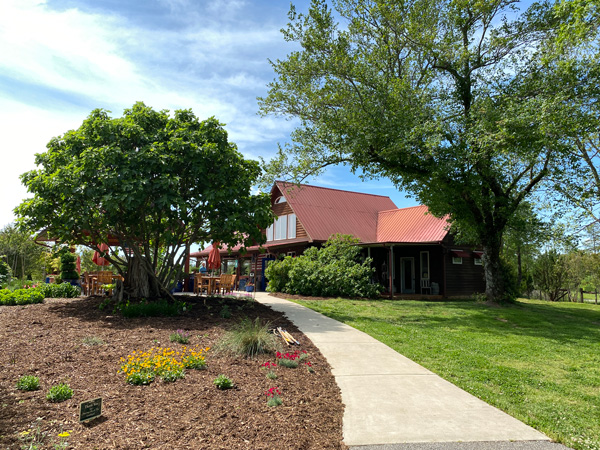 Overmountain Vineyards Tryon NC with wine tasting house with paved walkway, green trees, and patio