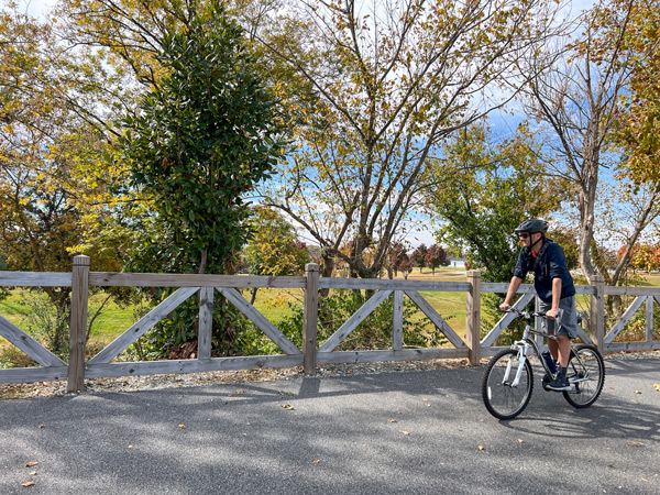 Tom biking along fence and trees