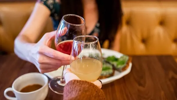 Tupelo Honey Asheville NC with white brunette woman doing a red and orange mimosa cheers with plate of avocado toast
