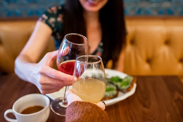 Tupelo Honey Asheville NC with white brunette woman doing a red and orange mimosa cheers with plate of avocado toast