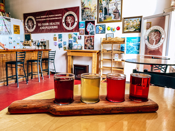 Black Mountain Cider and Mead flight of cider and mead on a table with bar in the background