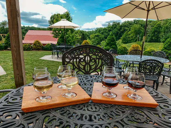 Linville Falls Winery NC two wine flights with red and white wines on table looking out over green grass