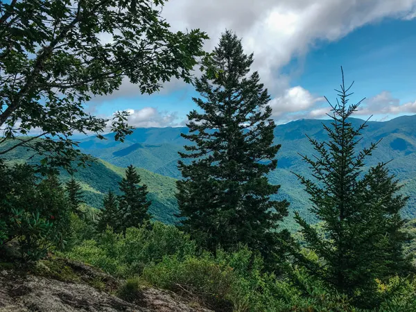 Little Butt Trail Overlook NC with Black Mountains, cloudy sky, and green trees