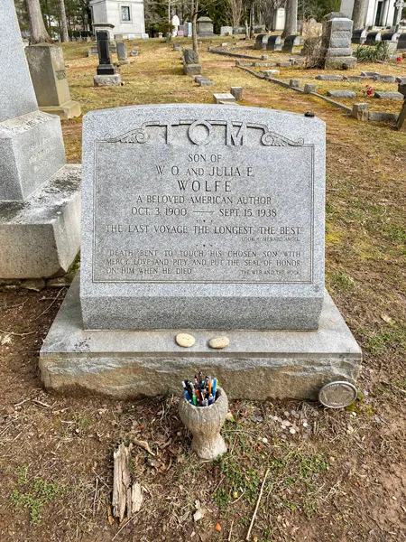 Thomas Wolfe Gravestone at Riverside Cemetery in Asheville NC with vase filled with pens and green grass