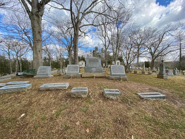 Wolfe Family Tombstones at Riverside Cemetery in Historic Montford with multiple gray and taller graves and flat and smaller stones in front on green-brown grass