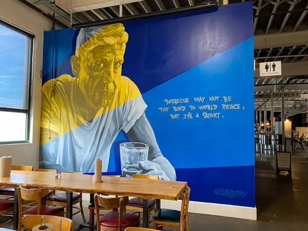 12 Bones Smokehouse Brewery South Asheville with mural of Anthony Bourdain with travel quote in blues and yellow by Gus Cutty