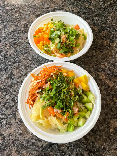 Aloha Cafe in Downtown Asheville, NC Sushi bowls filled with cilantro, raw sushi and salmon, carrots, mango, masago, and ginger on marble countertop