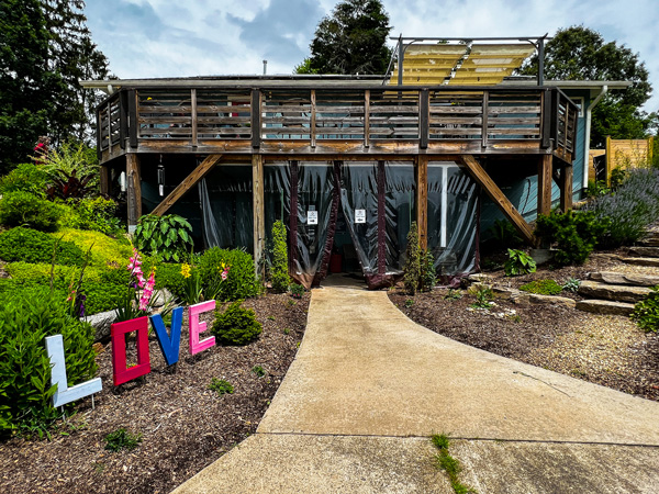 Asheville Salt Cave Entrance with back of house with deck with tarp and sign that says love out front