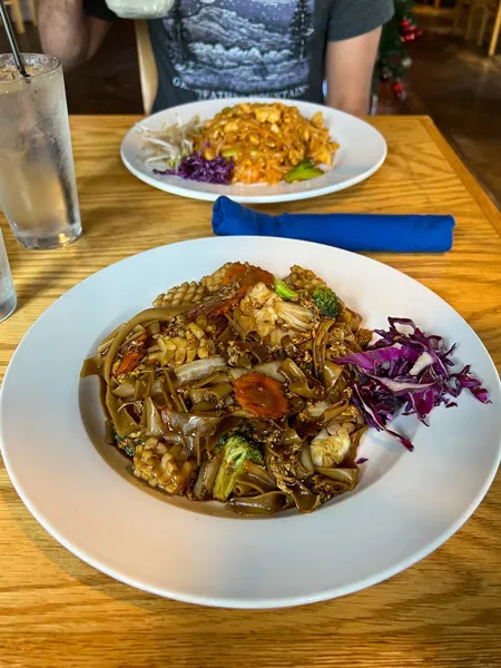 Asian Fusion Kitchen Restaurant Morganton NC with two white plates on table, one with Pad Thai noodles and the other with Pad See Ew with noodles, carrots, and squid