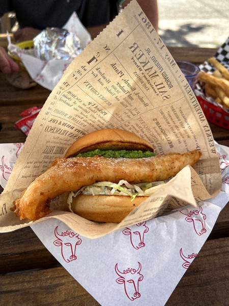 Baby Bull Asheville Restaurant with Fried Fish Sandwich with lettuce and bun in basket with paper and side of fries in the background