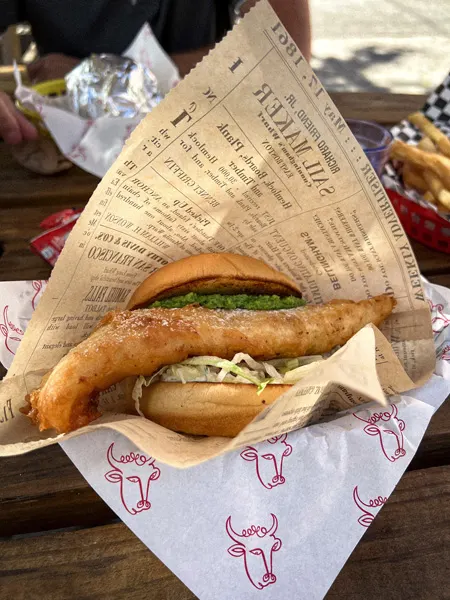 Baby Bull Asheville Restaurant with Fried Fish Sandwich with lettuce and bun in basket with paper and side of fries in the background