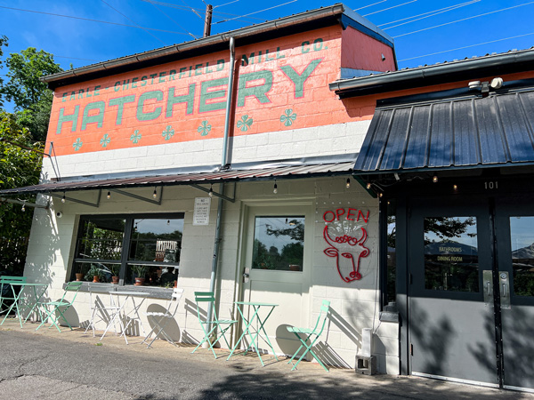 Baby Bull Restaurant in the River Arts District in Asheville NC facade with white and orange coloring and sign that says Hatchery