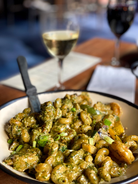 Best Restaurants In Asheville Nine Mile Montford with bowl of pasta with dairy free pesto, shrimp, veggies, and glass of white wine