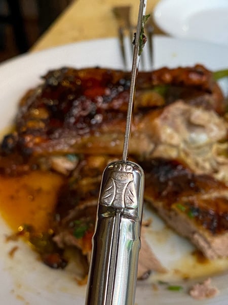 Close up of knife with bee engraved on it in front of duck entree at Bouchon French Restaurant in Downtown Asheville NC 
