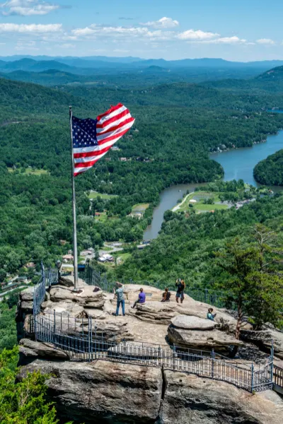 Chimney Rock State Park with rock, view of Lake Lure, and American flag blowing in the breeze