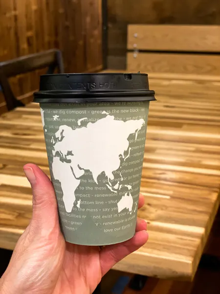 Coffee Asheville Chocolate with world map in green on takeaway mug over wooden table