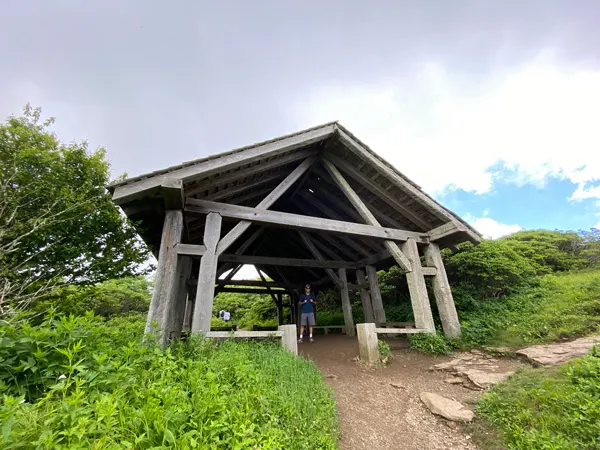 Craggy Gardens Trail Shelter with white brunette male under an open but covered wooden structure