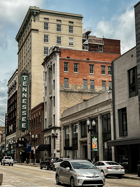 Downtown Knoxville TN Gay Street with buildings and cars on road with sign that says Tennessee