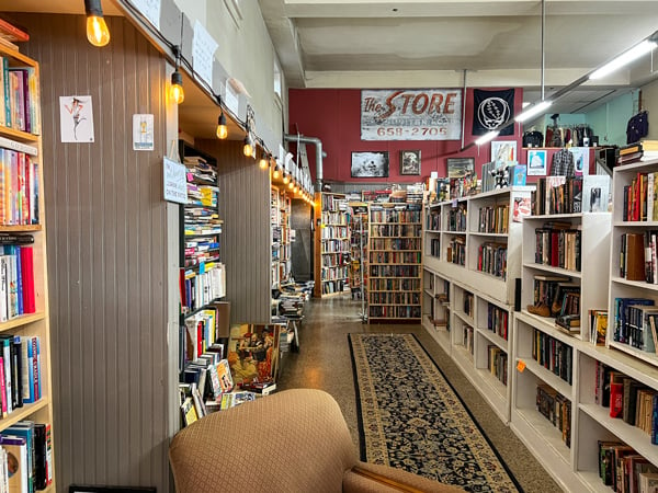 French Broad Exchange in Marshall NC Used Bookstore with aisle surrounded by full bookshelves and old brown armchair