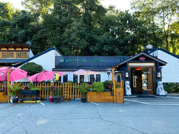 Green Tea Sushi Restaurant Asheville NC with picture of building and parking lot with patio and tables with red umbrellas
