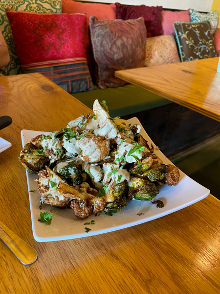 Gypsy Queen Cuisine Best Vegan and Gluten-free Restaurant Asheville NC with plate of mixed fried cauliflower and Brussel sprouts