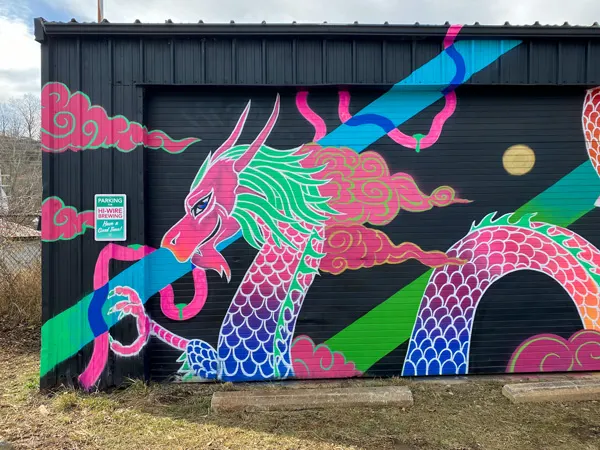 Hi-Wire Beer Garden River Arts District with mural of pink, purple, blue and green dragon in parking lot