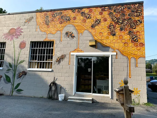 Honey and the Hive Mural Weaverville NC with rectangle building with honey, bee, and flower mural above door