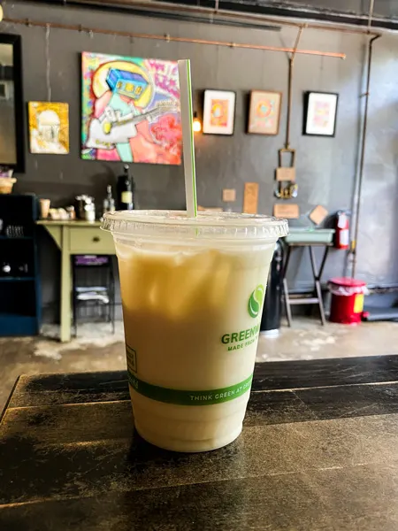 Izzys Coffee Asheville NC with iced coffee on table with art in background