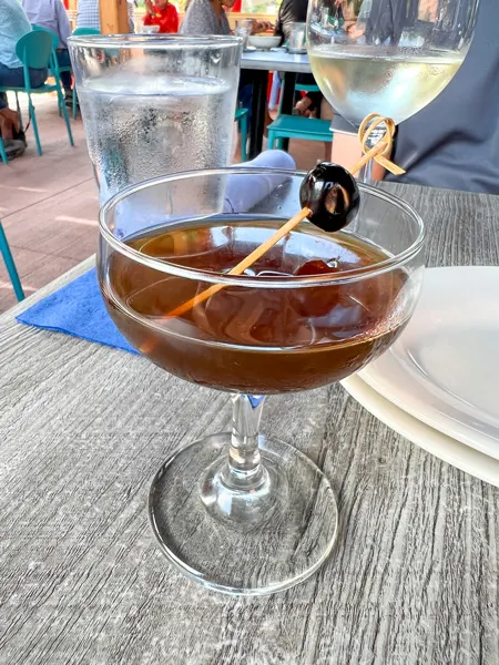 Jettie Rae's Oyster House in Asheville NC brown Cocktail on gray table with dark cherry garnish