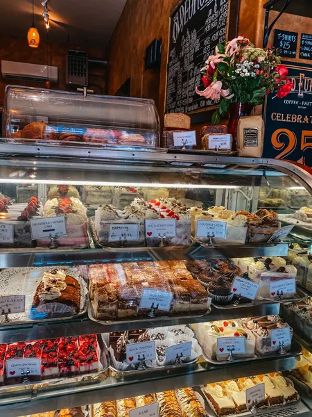 Old Europe Pastries Asheville NC with filled up pastry display glass, flowers, and menu board