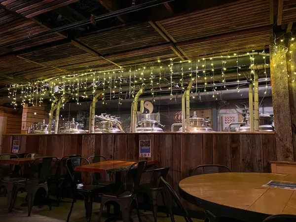One World Brewing Downtown Asheville NC with dark underground taproom with fermentation beer tanks, yellow Christmas lights, and tables