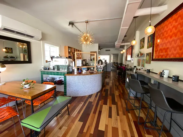 PennyCup Coffee Co Asheville NC with green, black, and orange benches and chairs, bar, fancy light, and orange picture