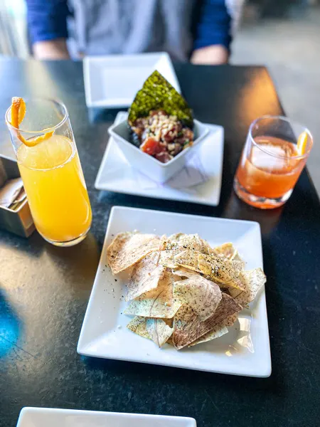 RosaBees Restaurant RAD Asheville with raw seafood, taro chips, and yellow and orange cocktails