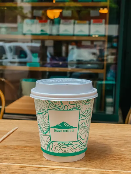 Summit Coffee Co Downtown Asheville with to-go coffee cup with lid in front of coffeeshop storefront