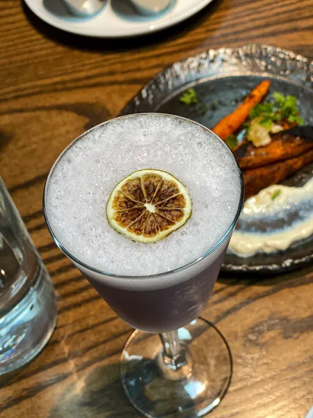 Ukiah Japanese Restaurant Asheville cocktail with purple coloring, bubbles, and lemon garnish