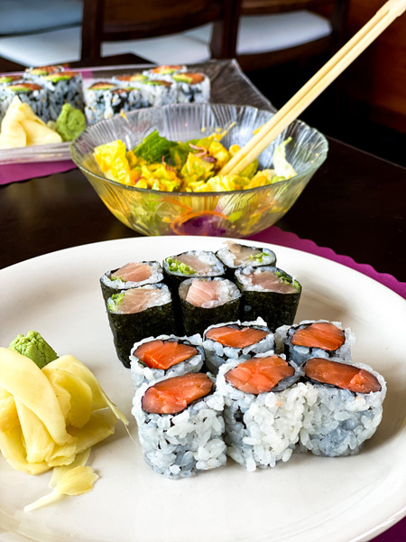 Umi Sushi Near Asheville with picture of yellow tail and salmon sushi rolls with ginger salad with chopsticks