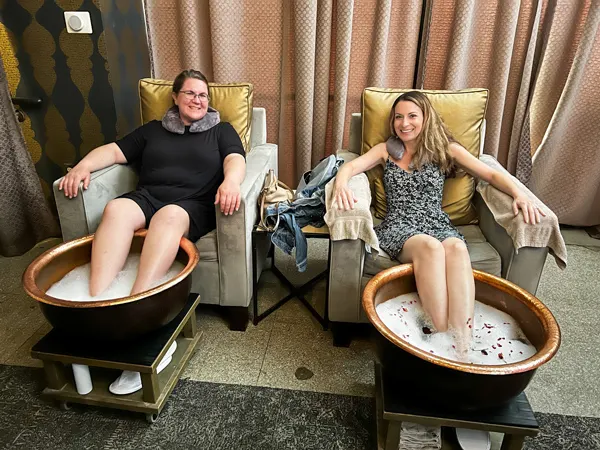 Wake Foot Sanctuary Day Spa Asheville NC with two white women in dresses sitting in armchairs with foot soak tubs in front of them