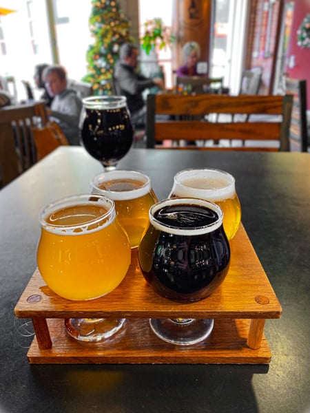 White Labs Brewing Co Asheville NC Flight with three yellow beers and one dark stout on table with full pour in the background