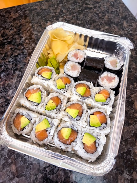 Zen Asheville NC Sushi Takeout with twelve salmon and avocado rolls with six yellowtail and scallion rolls in takeaway container with ginger and wasabi