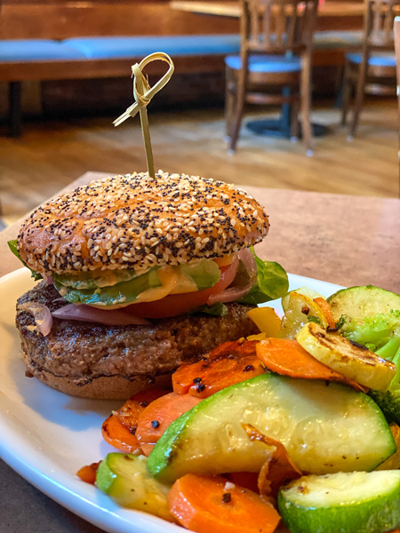 Burger from Twisted Laurel Weaverville on gluten-free bun with side of veggies like carrots and zucchini