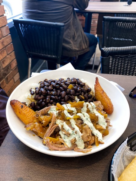 Cousins Cuban Cafe bowl filled with fried plantains, beans, and mojo pork